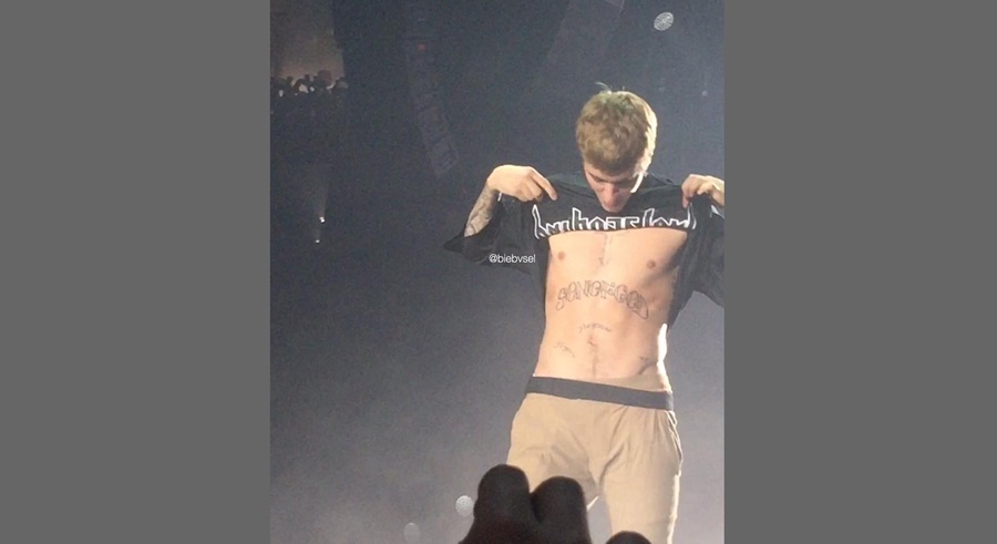 Justin Bieber showing his Son Of God chest tattoo shirtless on stage